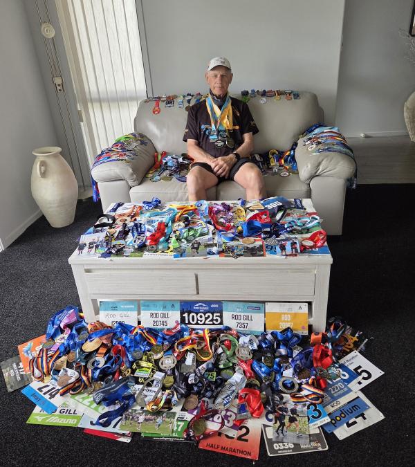 Rod Gill proudly displays his collection of 199 half marathon medals accumulated over the past 10 years. Credit Supplied